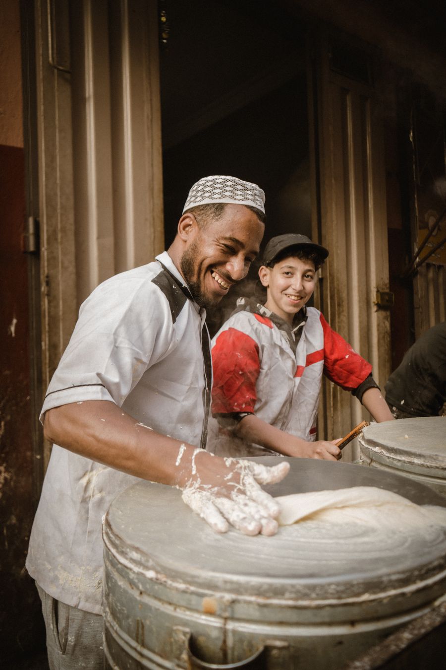 Panaderos sonriendo mientras preparan el pan